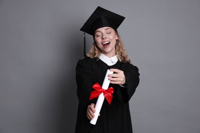 Photo of Happy student with diploma after graduation on grey background