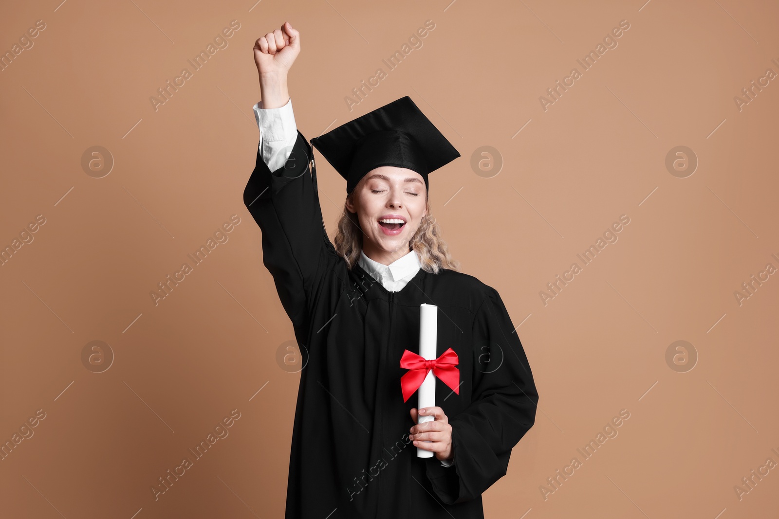 Happy student with diploma after graduation on beige background Photo of Happy student with diploma after graduation on beige background