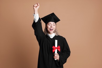 Photo of Happy student with diploma after graduation on beige background