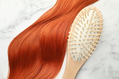 Image of Wooden brush and lock of hair on white marble table, top view