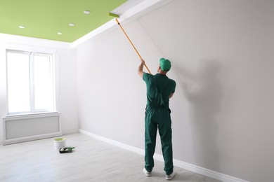 Image of Man painting ceiling with green dye indoors