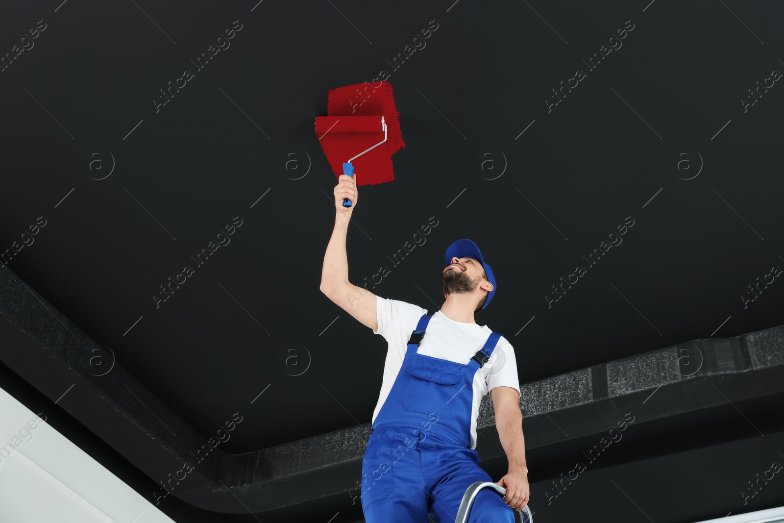 Man repainting black ceiling with red dye indoors, low angle view Image of Man repainting black ceiling with red dye indoors, low angle view
