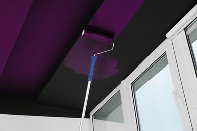 Image of Painting black ceiling with purple dye indoors, low angle view