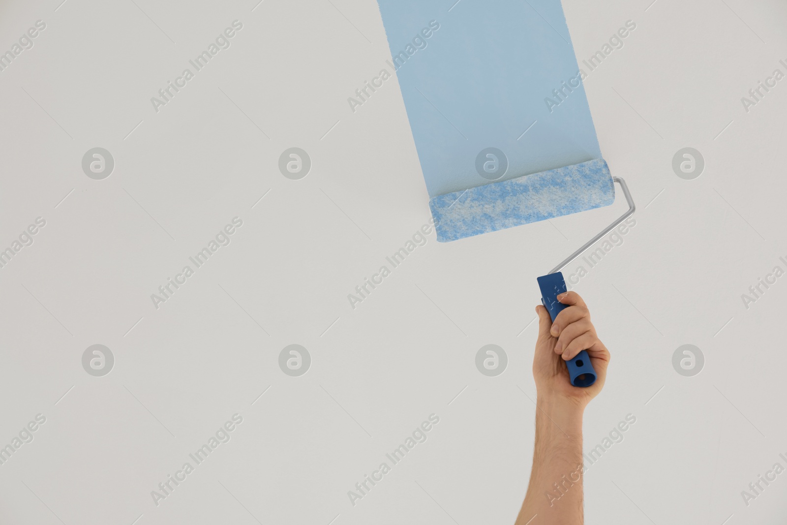 Man white painting ceiling with light blue dye indoors, low angle view Image of Man white painting ceiling with light blue dye indoors, low angle view