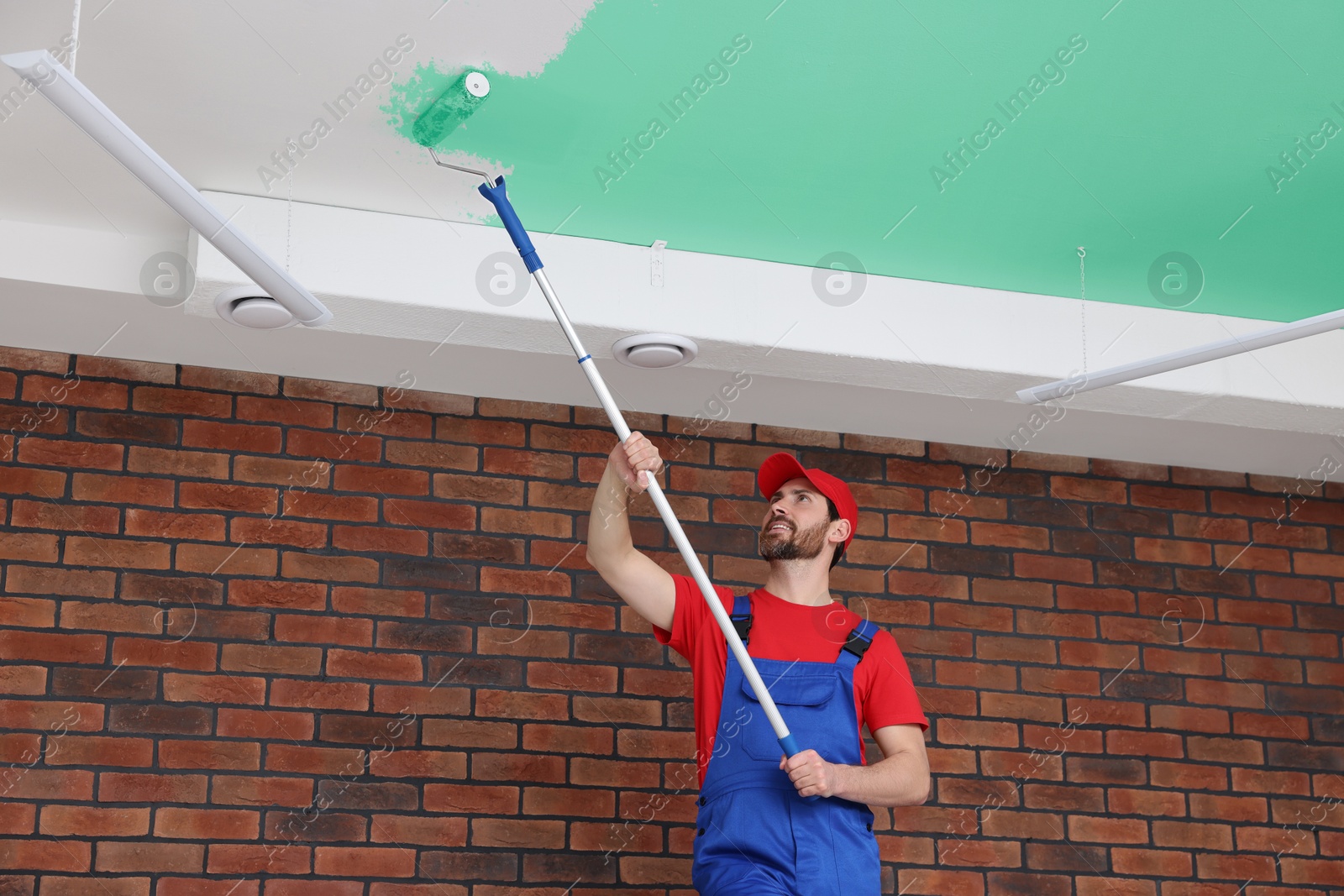 Man painting white ceiling with aquamarine dye indoors, low angle view Image of Man painting white ceiling with aquamarine dye indoors, low angle view