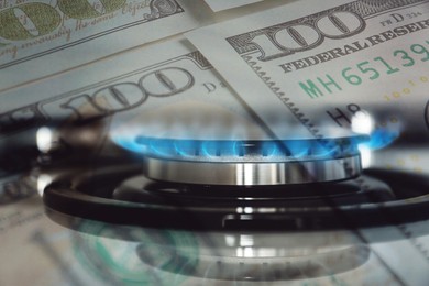 Image of Gas burner with blue flame and dollar bills, double exposure. Gas tariff