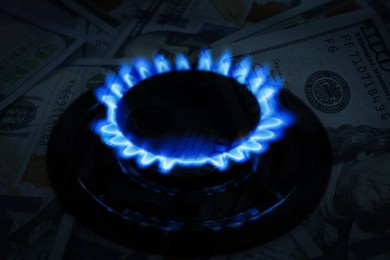 Image of Gas burner with blue flame and dollar bills, double exposure. Gas tariff