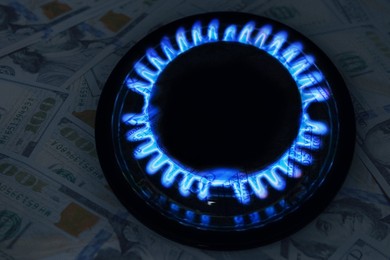 Image of Gas burner with blue flame and dollar bills, double exposure. Gas tariff
