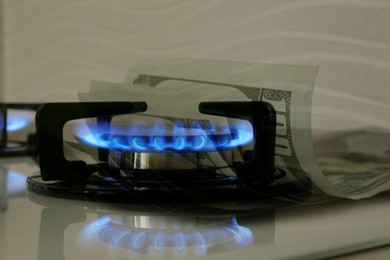 Image of Gas burner with blue flame and dollar bills, double exposure. Gas tariff