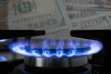 Image of Gas burner with blue flame and dollar bills, double exposure. Gas tariff