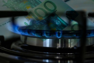 Image of Gas burner with blue flame and euro bills, double exposure. Gas tariff