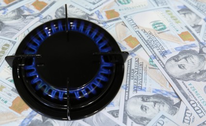 Image of Gas burner with blue flame and dollar bills, double exposure. Gas tariff