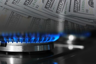 Image of Gas burner with blue flame and dollar bills, double exposure. Gas tariff