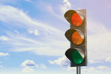 Image of Traffic lights against blue sky with clouds