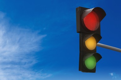Image of Traffic lights against blue sky with clouds