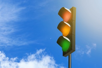 Image of Traffic lights against blue sky with clouds