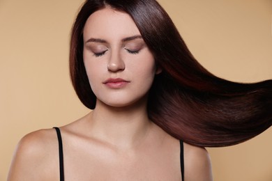 Image of Beautiful young woman with shiny healthy hair on dark beige background
