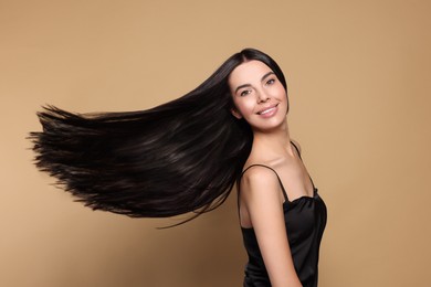 Image of Beautiful young woman with shiny healthy hair on dark beige background