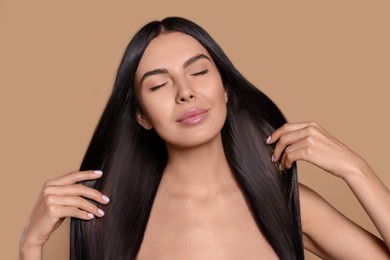 Image of Beautiful young woman with shiny healthy hair on dark beige background
