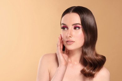Image of Beautiful young woman with shiny healthy hair on dark beige background