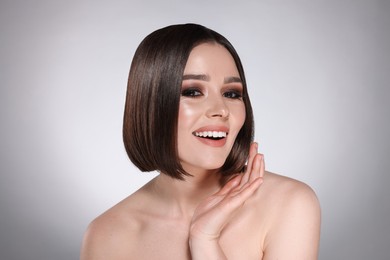 Image of Beautiful young woman with shiny healthy hair on grey background