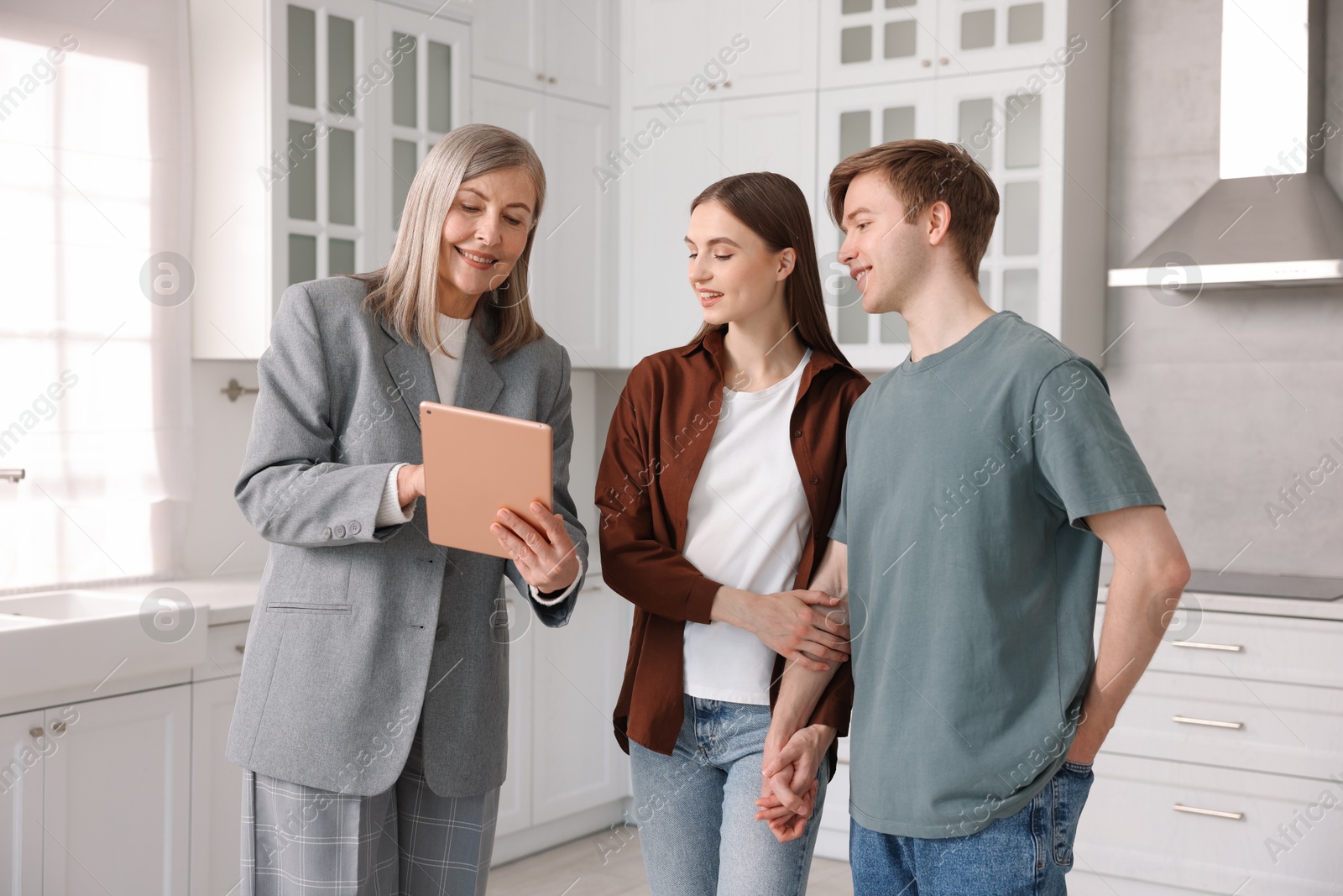 Smiling real estate agent with tablet working with couple in kitchen Photo of Smiling real estate agent with tablet working with couple in kitchen