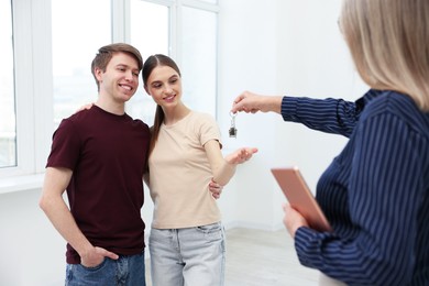 Photo of Real estate agent with tablet giving house key to new owner at home, closeup