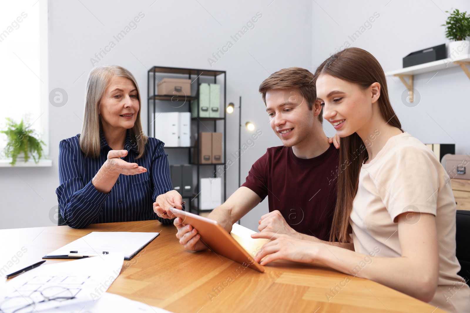 Real estate agent and couple with tablet at table in office Photo of Real estate agent and couple with tablet at table in office
