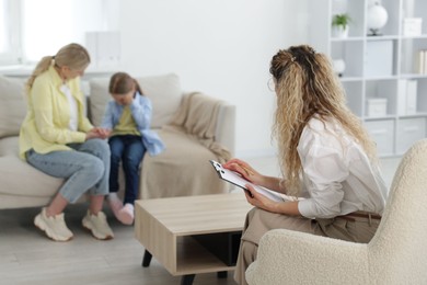 Photo of Mother and daughter having consultation with psychologist in office, selective focus