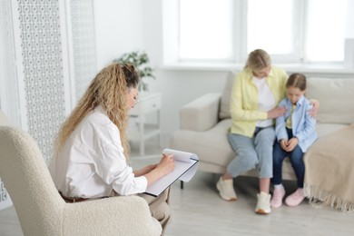 Photo of Mother and daughter having consultation with psychologist in office, selective focus