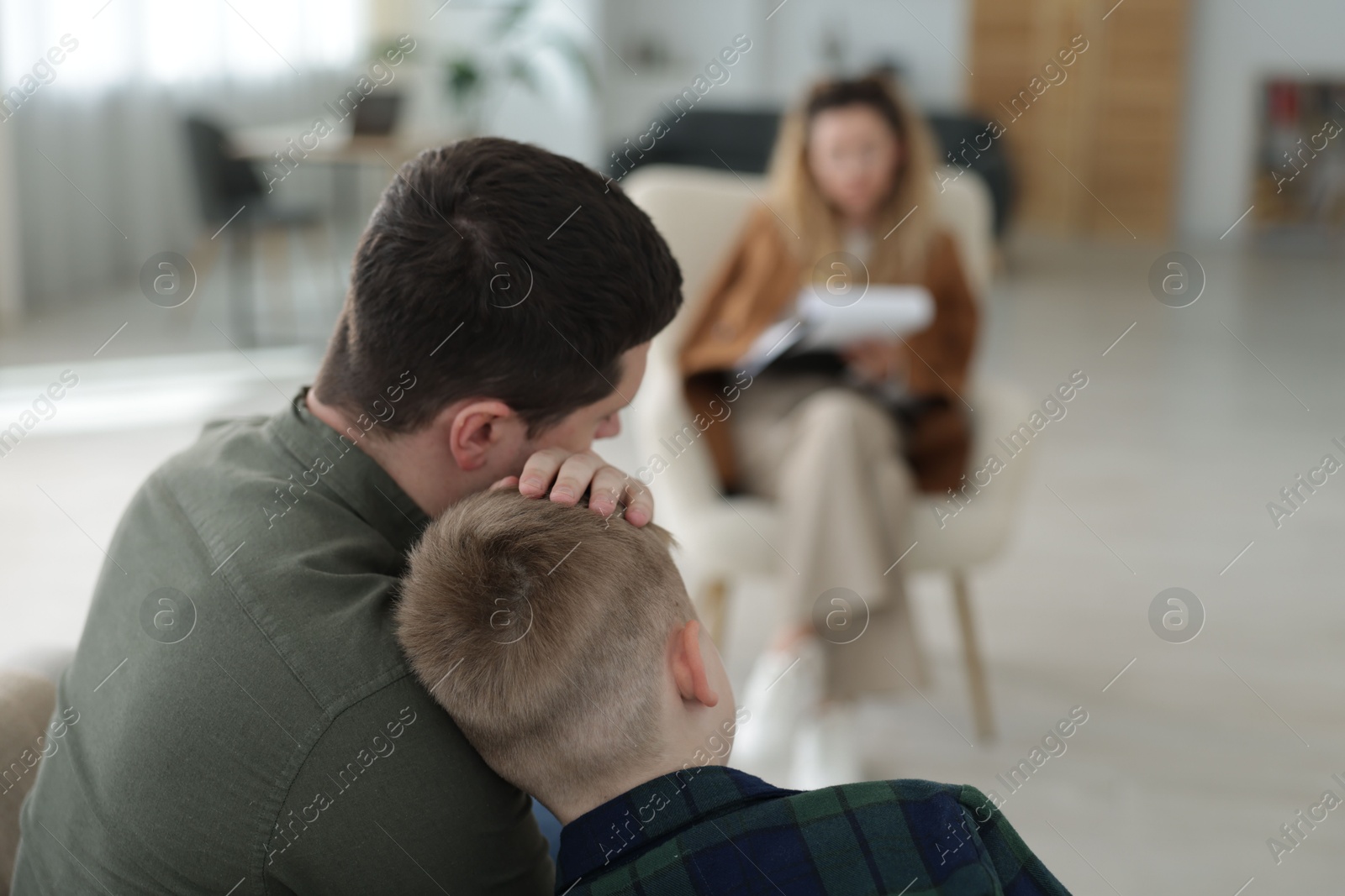 Father and son having consultation with psychologist in office, selective focus. Space for text Photo of Father and son having consultation with psychologist in office, selective focus. Space for text
