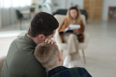 Photo of Father and son having consultation with psychologist in office, selective focus. Space for text