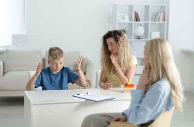 Photo of Mother and son having consultation with psychologist in office, selective focus