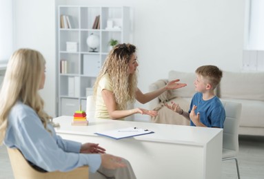 Photo of Mother and son having consultation with psychologist in office, selective focus