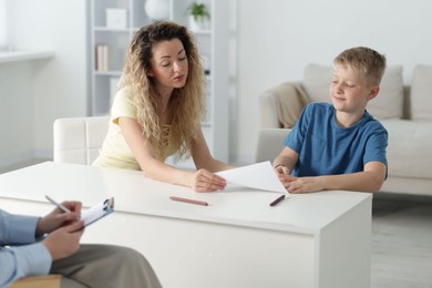 Photo of Mother and son having consultation with psychologist in office, selective focus