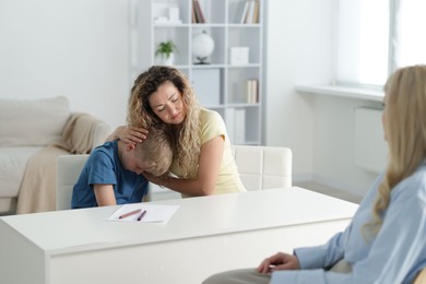 Photo of Mother and son having consultation with psychologist in office, selective focus