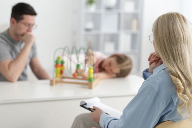 Photo of Father and daughter having consultation with psychologist in office, selective focus