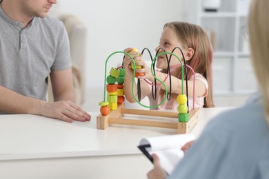 Photo of Father and daughter having consultation with psychologist in office, selective focus
