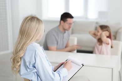 Photo of Father and daughter having consultation with psychologist in office, selective focus