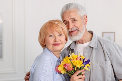 Photo of Lovely senior couple with bouquet of flowers at home