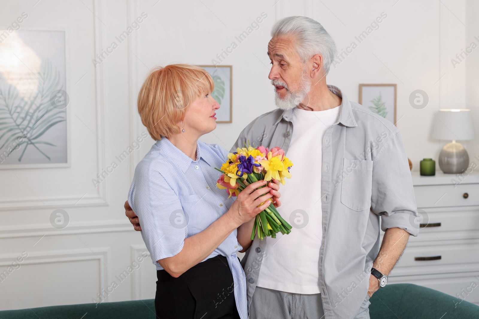Lovely senior couple with bouquet of flowers at home Photo of Lovely senior couple with bouquet of flowers at home
