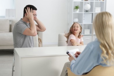 Photo of Father and daughter having consultation with psychologist in office, selective focus
