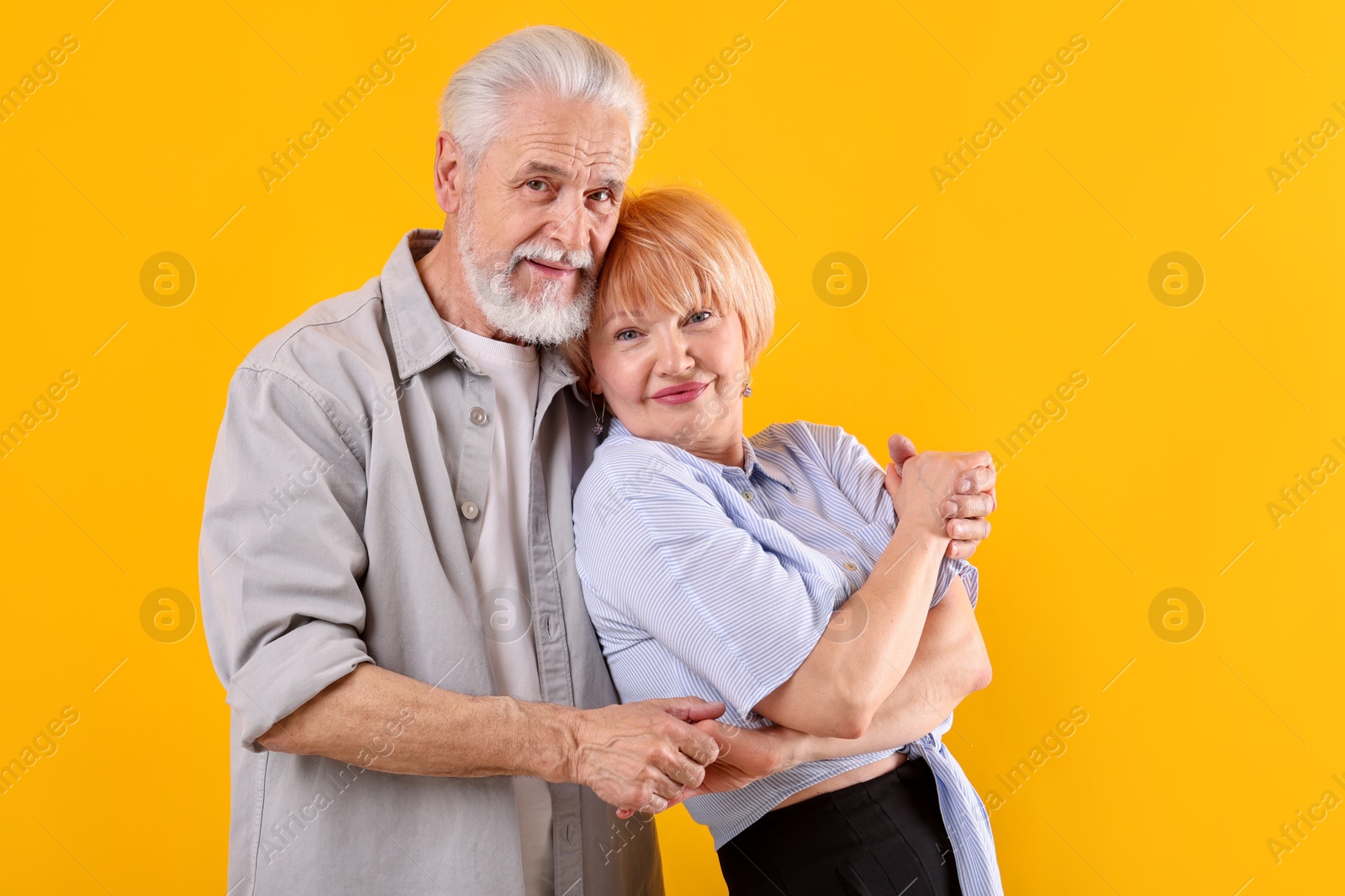 Lovely senior couple together on yellow background Photo of Lovely senior couple together on yellow background