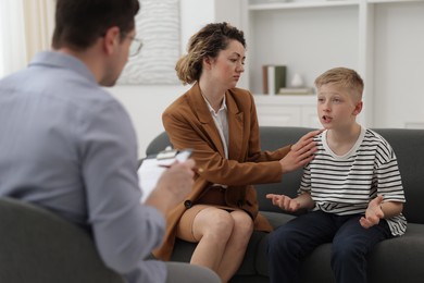 Photo of Mother and son having consultation with psychologist in office, selective focus