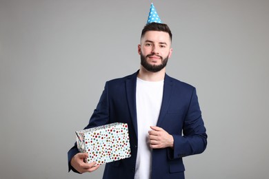 Photo of Happy Birthday. Handsome man with party hat and gift box on grey background