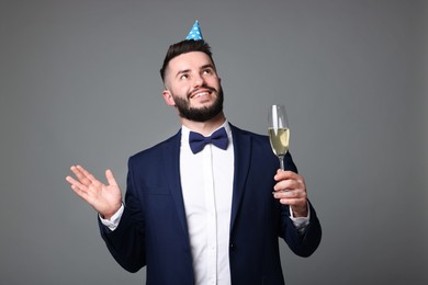 Photo of Happy Birthday. Handsome man with party hat and glass of champagne on grey background