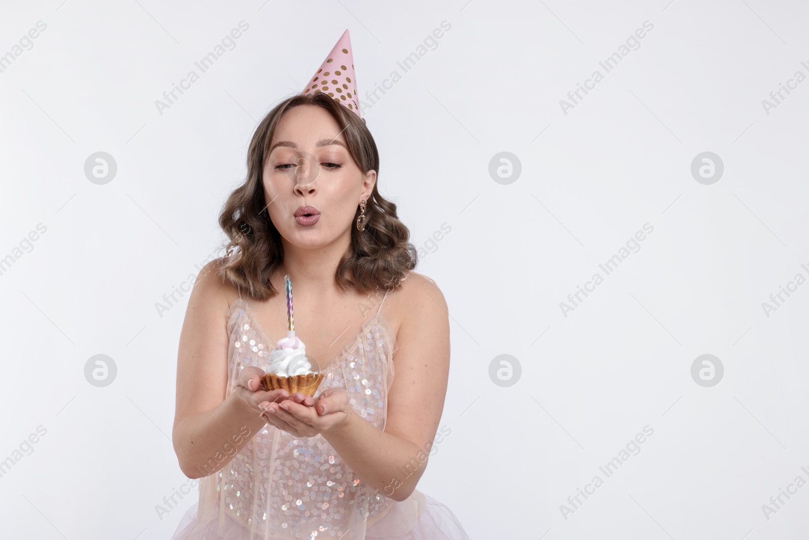 Birthday celebration. Woman blowing candle on cupcake against white background. Space for text Photo of Birthday celebration. Woman blowing candle on cupcake against white background. Space for text