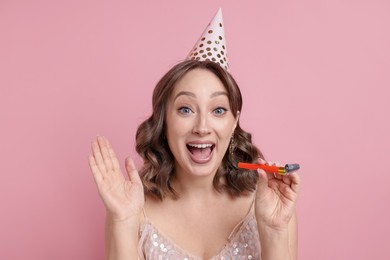Photo of Birthday celebration. Woman with party horn on pink background