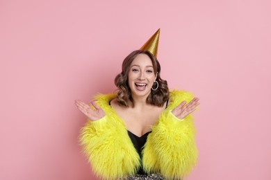 Photo of Birthday celebration. Happy woman with party cone on pink background