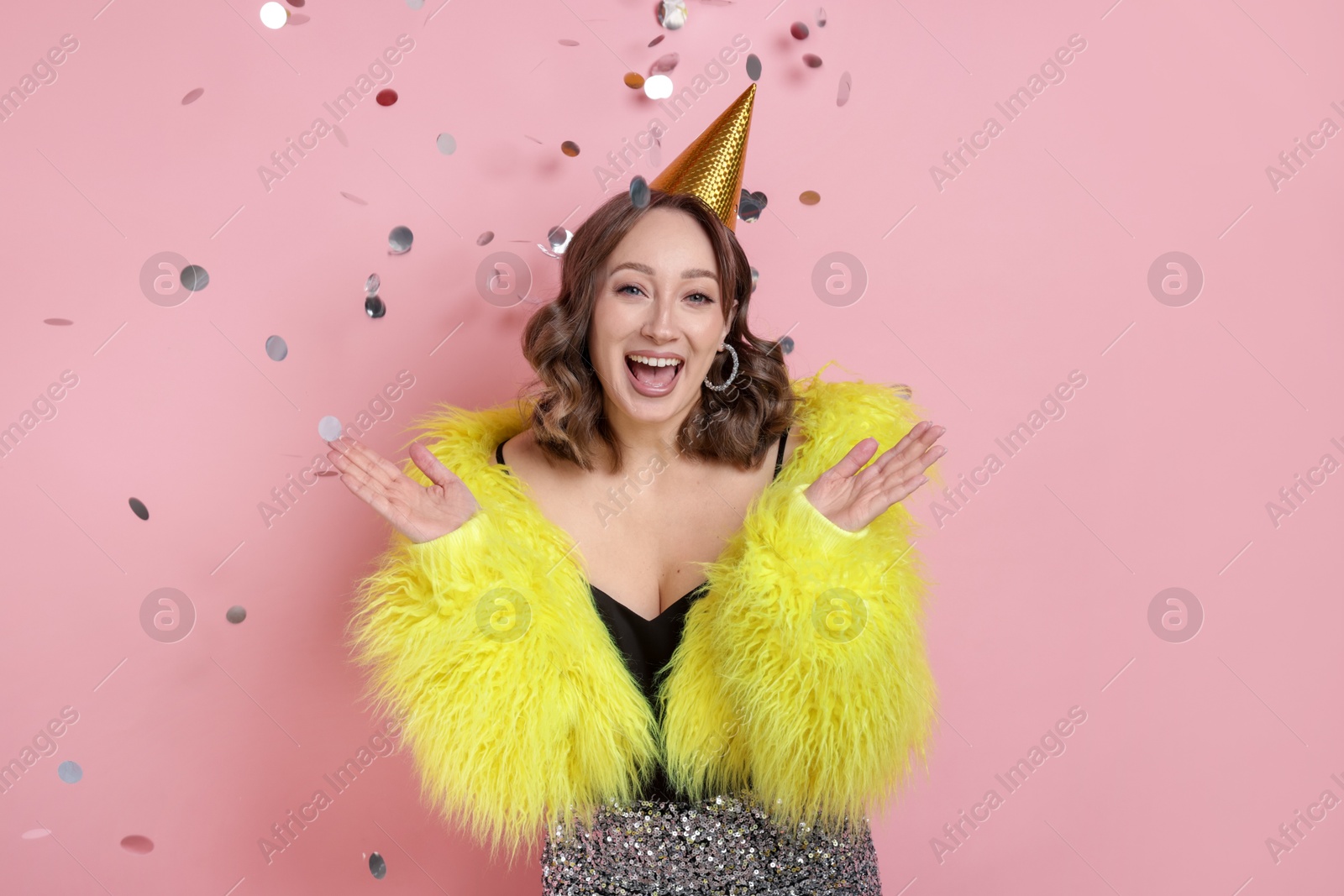 Birthday celebration. Woman on pink background with confetti Photo of Birthday celebration. Woman on pink background with confetti